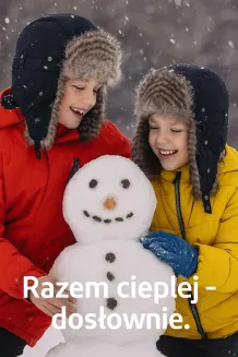 Rodzeństwo 8 i 10 lat w zimowych czapkach uszatkach dziecięcych W151K Polar Fashion, czarne pilotki ocieplane futerkiem, wspólne lepienie bałwana w padającym śniegu, widoczna para z ust, radość i ochrona przed mrozem.