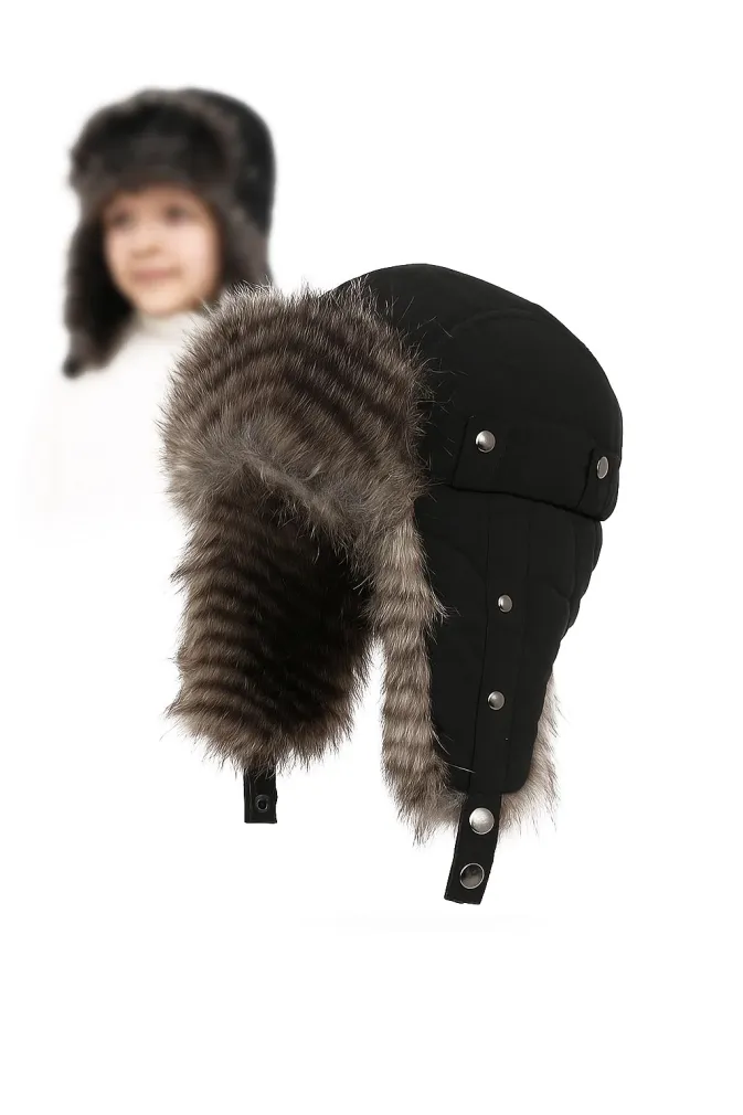 Czapka pilotka zimowa dziecięca W-151K czarna, uszatka impregnowana, z futerkiem, polar, zapięcie pod szyją, model dziecka w tle (głowa-szyja, białe ubranie), na idealnie białym tle.